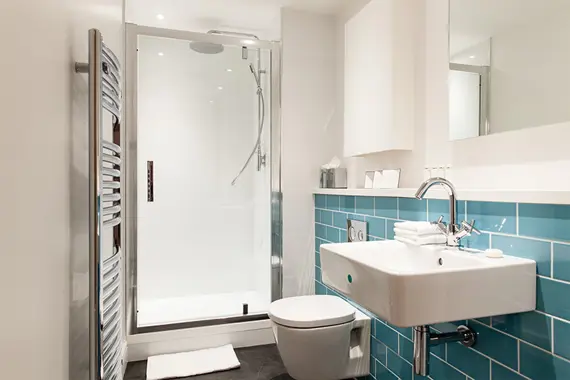 Turquoise blue tiled bathroom in a one bedroom apartment