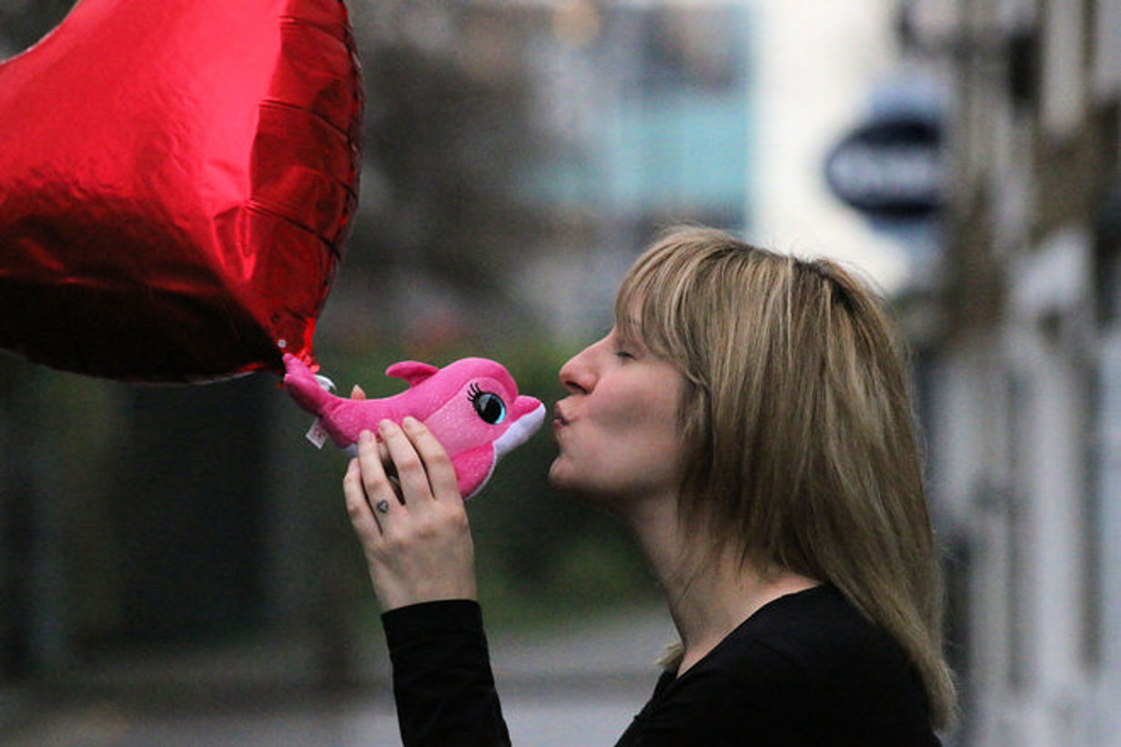 Girl kissing a pink dolphin and balloon loveheart